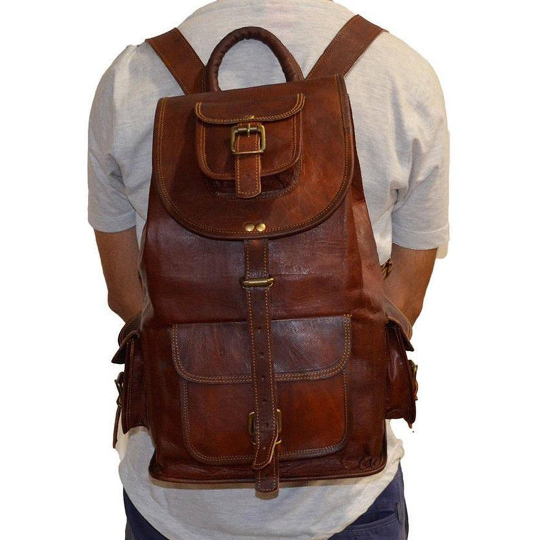 Brown leather backpack with top flap, center strap and stitched front pockets.