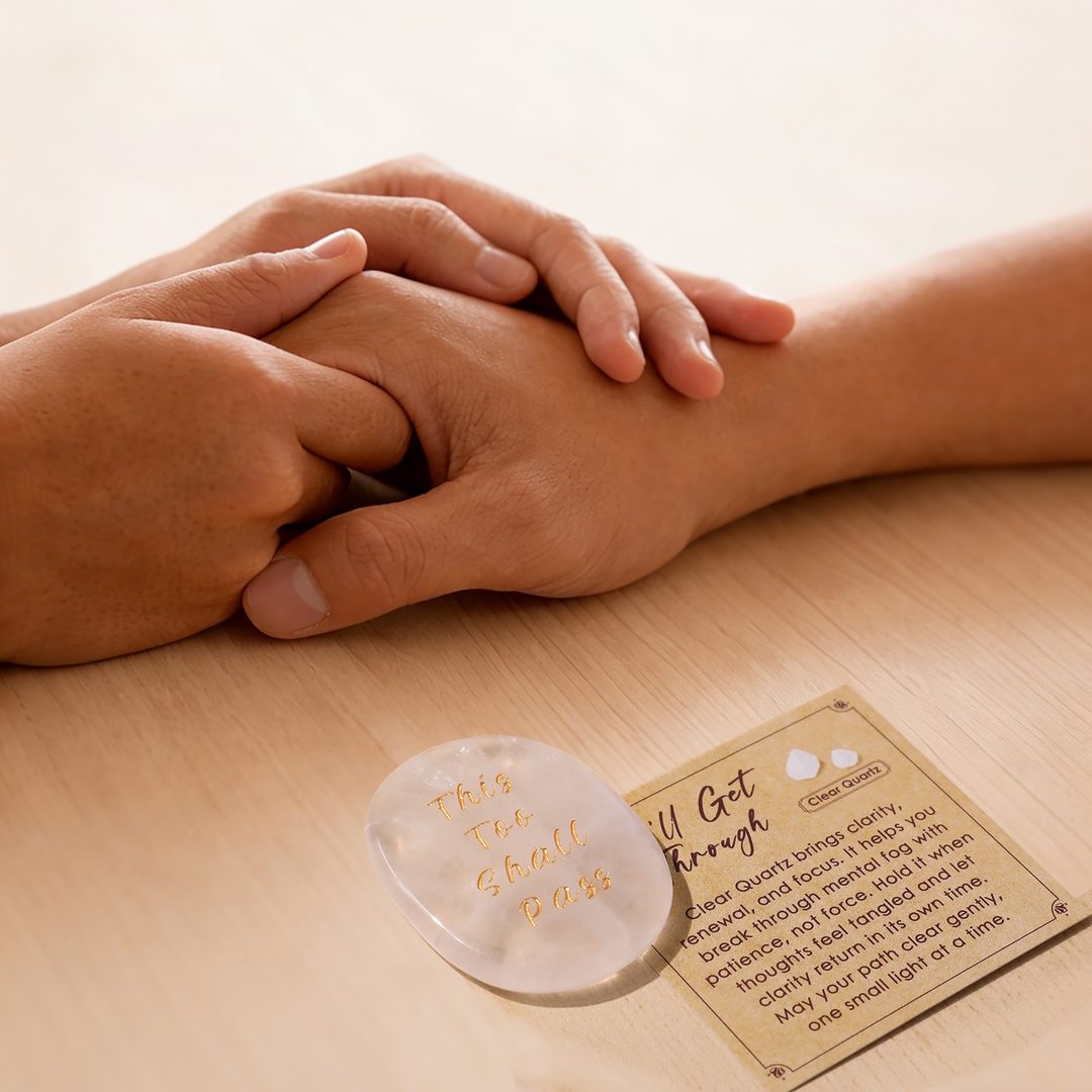 Gray heart-shaped crystal stone with gold lettering, beside instruction card