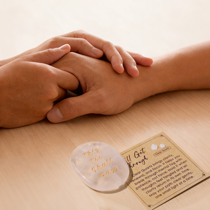 Gray heart-shaped crystal stone with gold lettering, beside instruction card