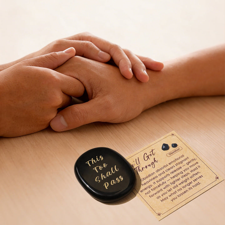 Black heart-shaped crystal stone with gold lettering, beside instruction card