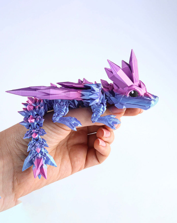 Purple and blue crystal wing baby dragon fidget toy held in hand, articulated spikes