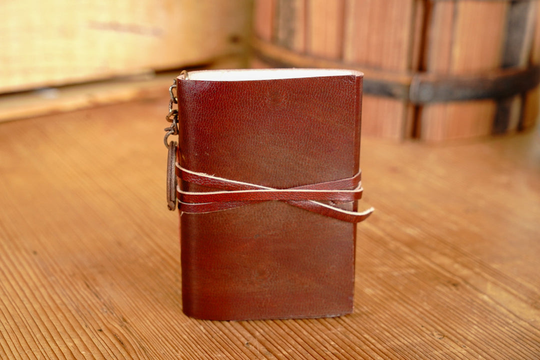 Distressed leather mini journal, dark red-brown cover with wrap strap and page edges