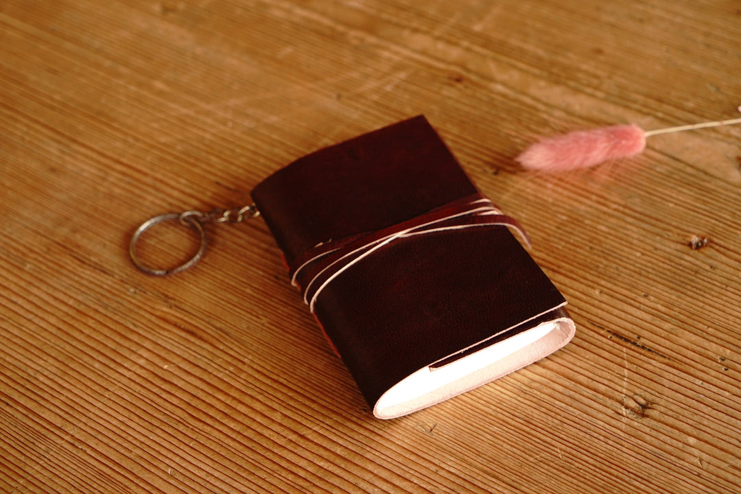 Distressed leather mini journal with keychain ring and wrap strap, dark red-brown