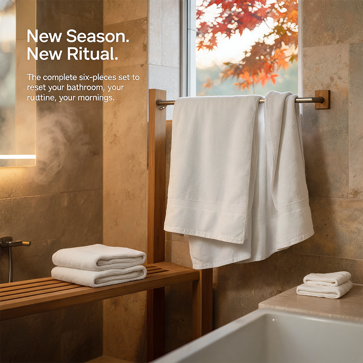 White bath towel set, two towels hanging and several folded towels on rack