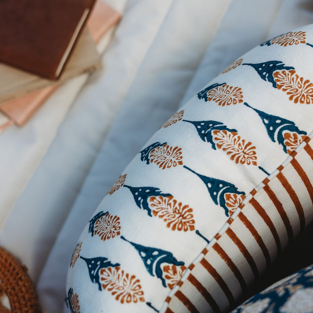 Throw pillow cover close-up with blue teardrop motifs and orange floral details