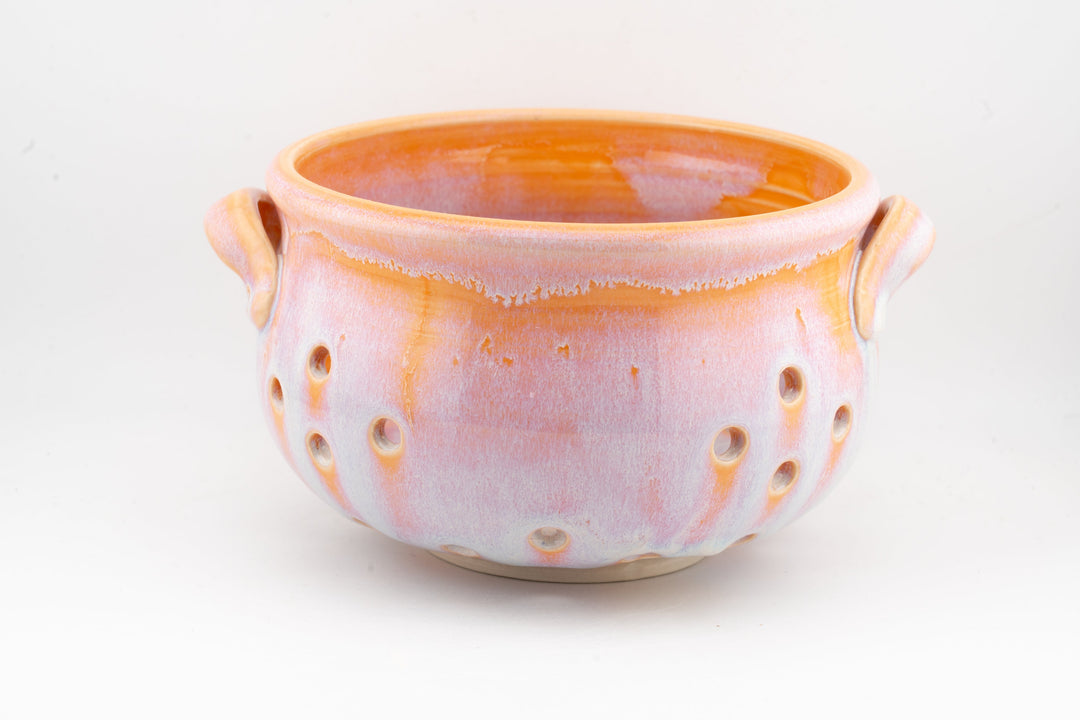 Handmade ceramic berry colander bowl with orange glaze, two side handles, perforated sides