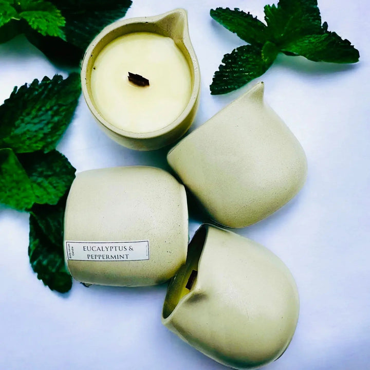 Body oil serum candle set with pale-green containers and white wax, visible wicks