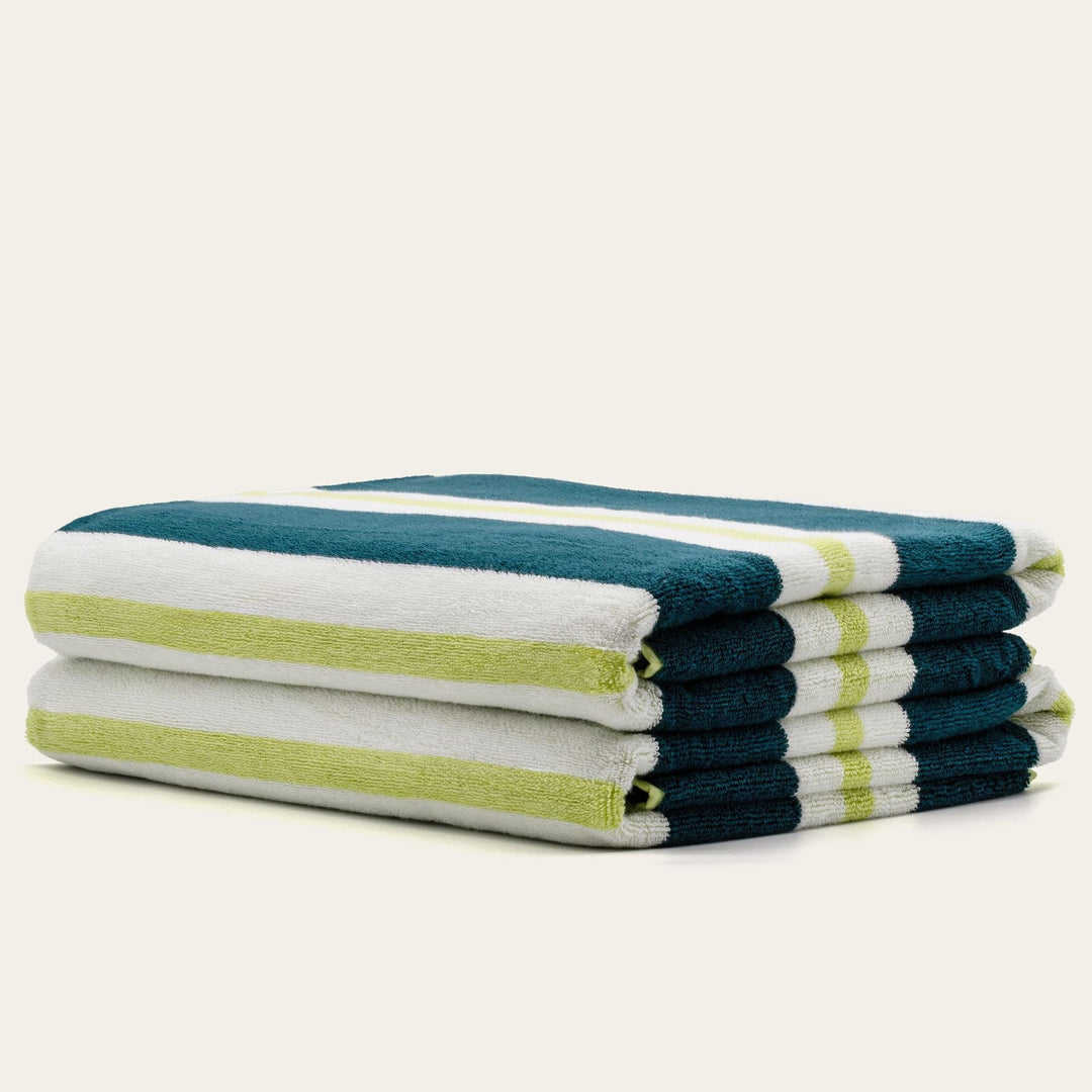 Cotton beach towels folded in teal, white, and green with striped bands