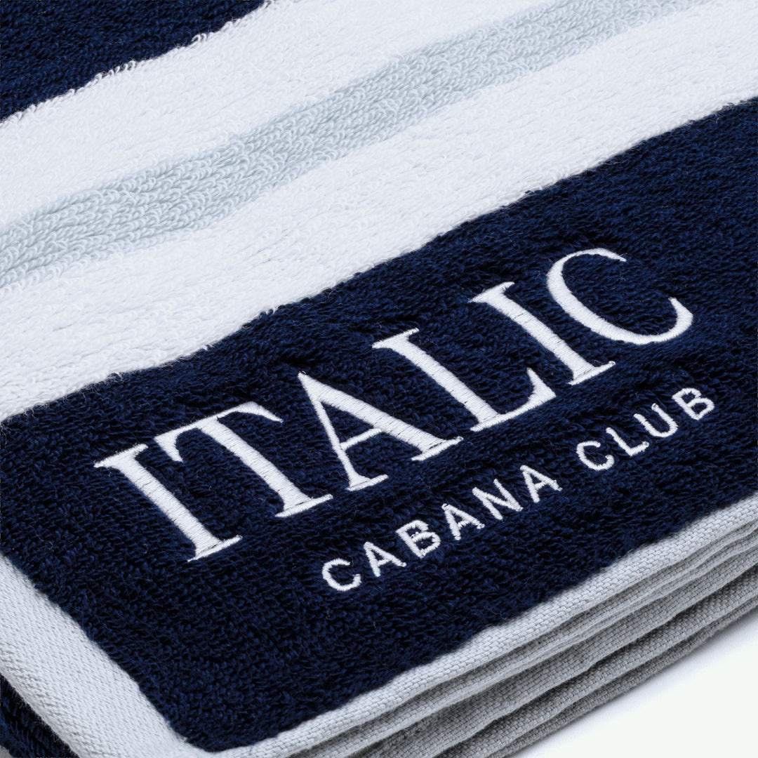 Close-up of navy cotton towel with white "ITALIC" and "CABANA CLUB"