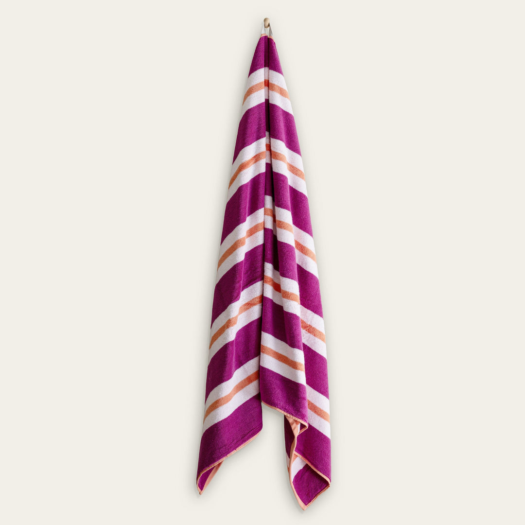 Cotton beach towel, magenta and cream striped with orange accents, folded