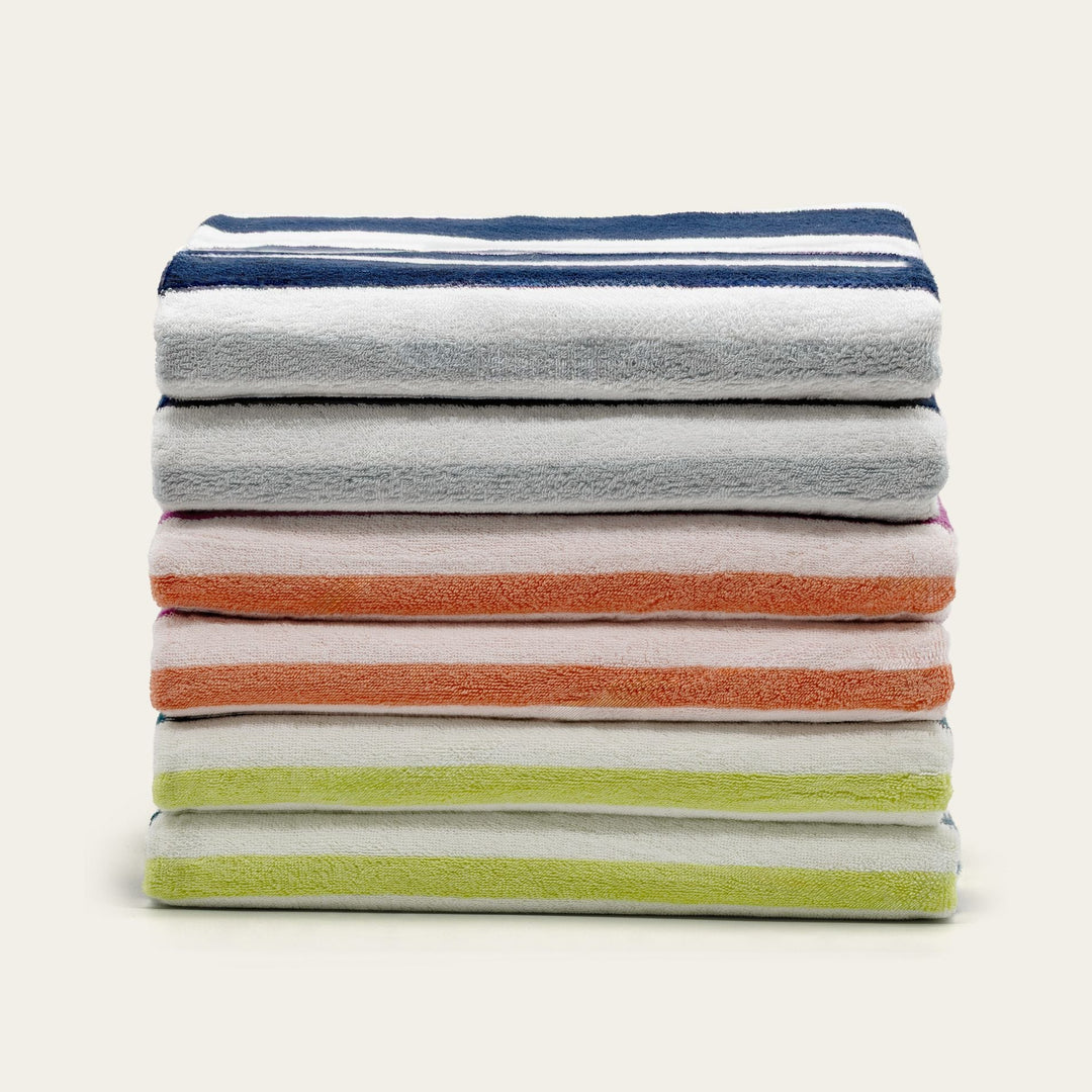 Stack of cotton beach towels in grey, orange, and light green stripes.