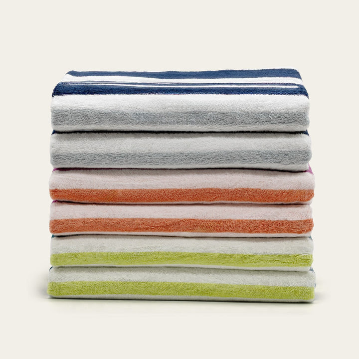 Stack of cotton beach towels in grey, orange, and light green stripes.