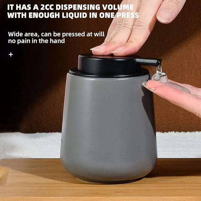 Large ceramic liquid soap dispenser, grey body with black pump, hand pressing