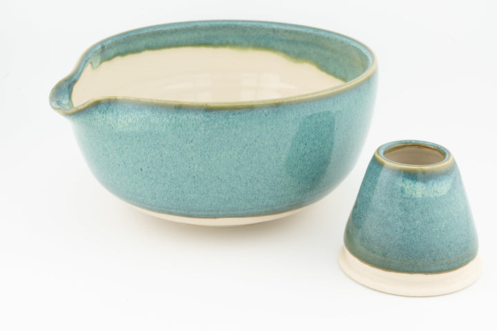 Turquoise ceramic matcha bowl with small spout and matching whisk stand.