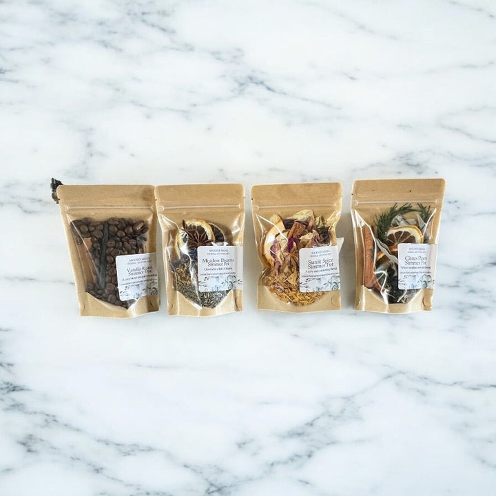 Four kraft paper simmer pot pouches with white labels, filled with dried ingredients.
