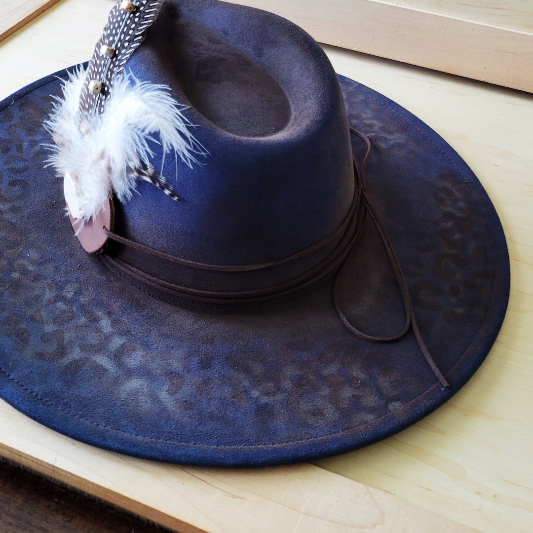 Navy blue leopard-print felt cowgirl hat with feathered beaded strap detail