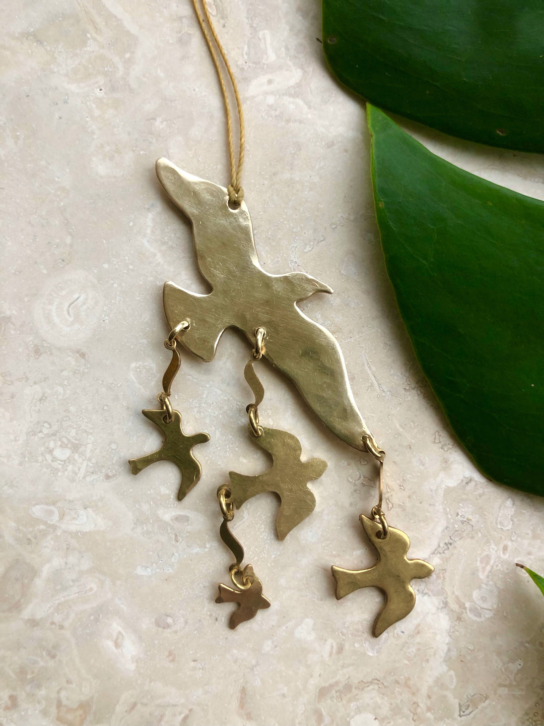 Gold-tone bird ornament with three dangling bird charms and star details on cord