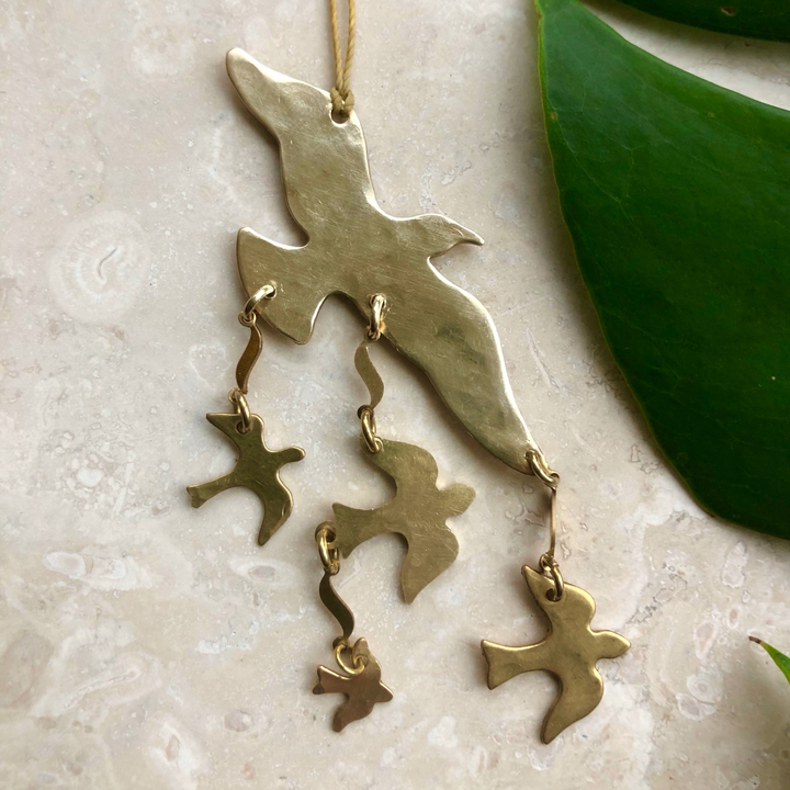 Brass bird ornament with dangling bird and star charms on a gold cord