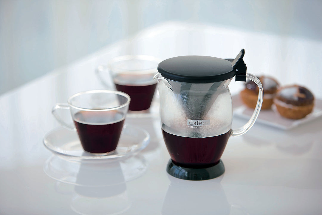 Iced coffee dripper with black lid and clear glass carafe holding dark coffee