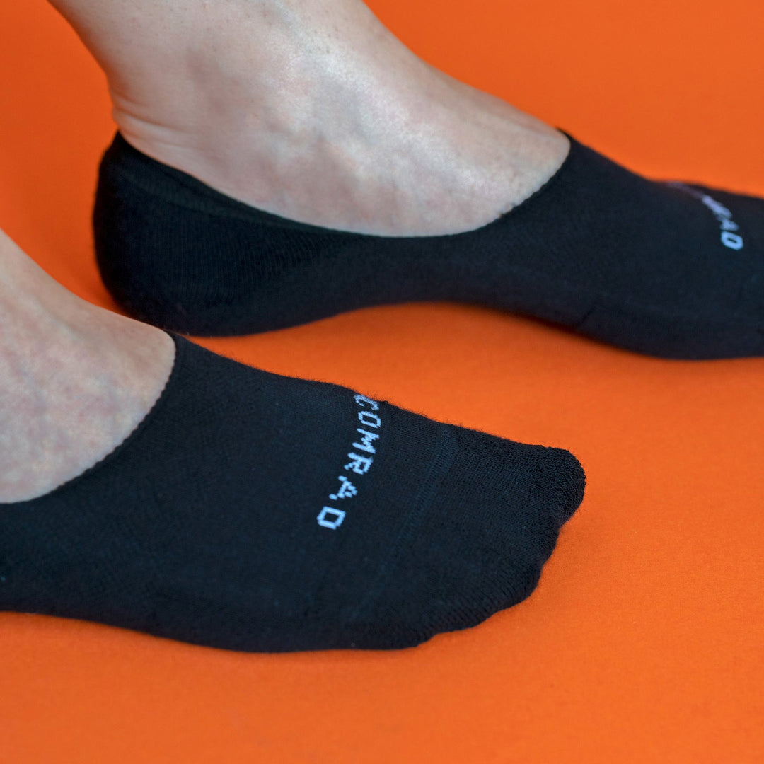 Black no-show socks close-up, smooth knit with brand lettering on the instep