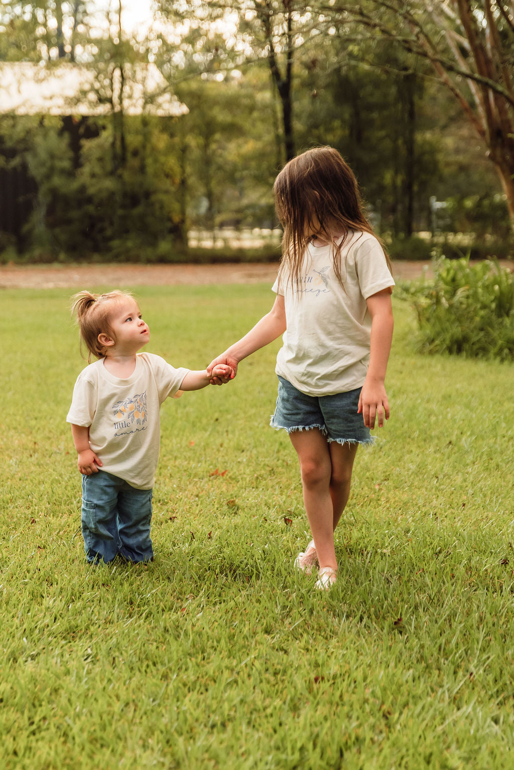 Kids organic cotton T-shirt, cream; child wearing leaf “little amore” front graphic.