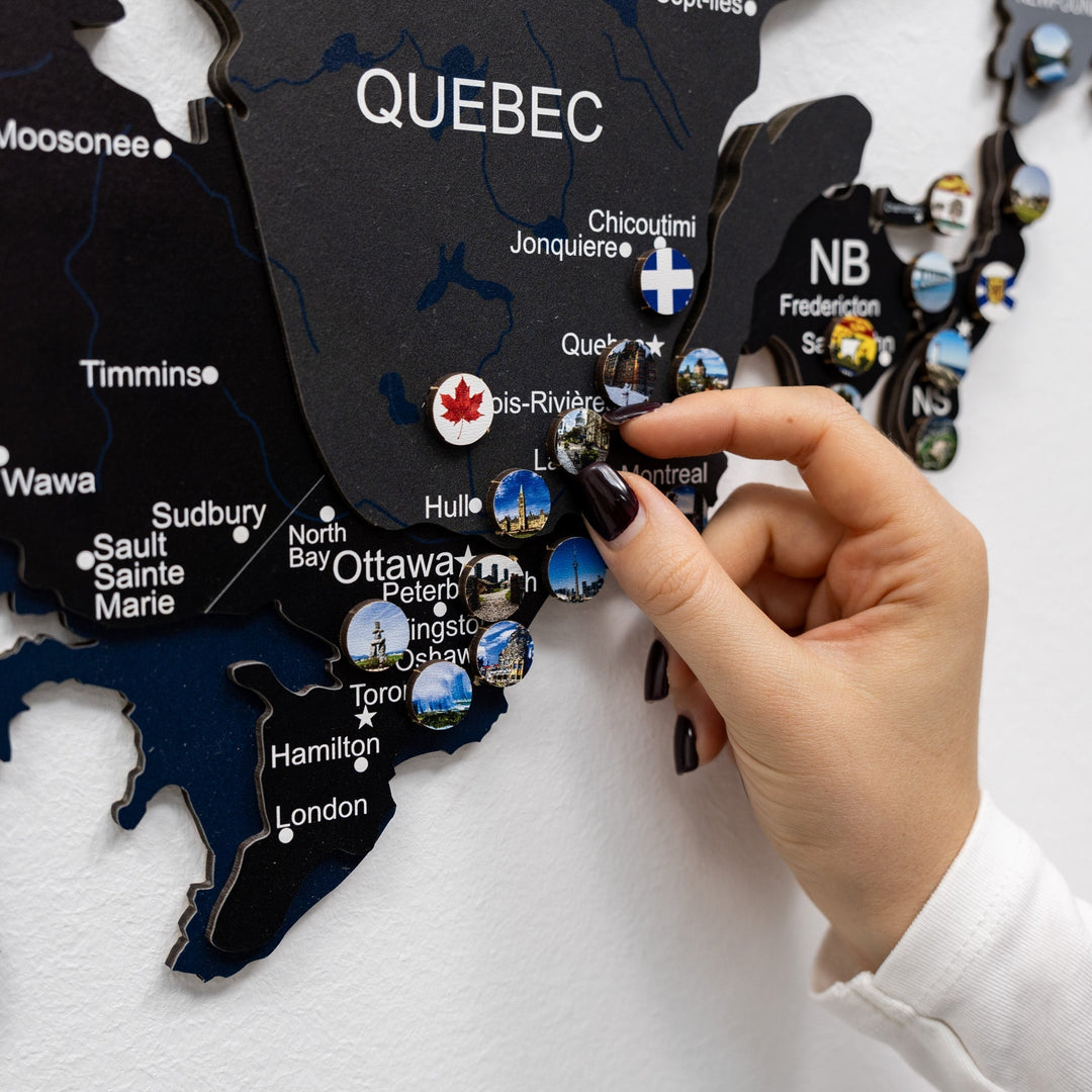 Canada landmarks pin set card raised by hands on wall map display with pins