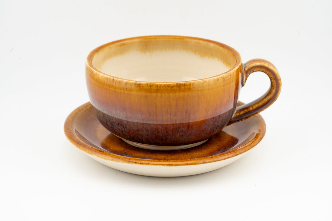 Orange-brown glazed cappuccino cup with matching saucer and curved side handle
