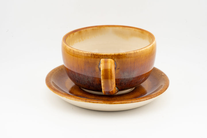 Orange-brown cappuccino cup with matching saucer, side handle and glossy glaze