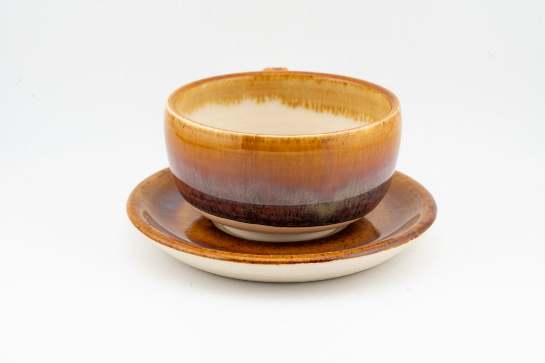 Orange-brown cappuccino cup with matching saucer, smooth glossy rim and base