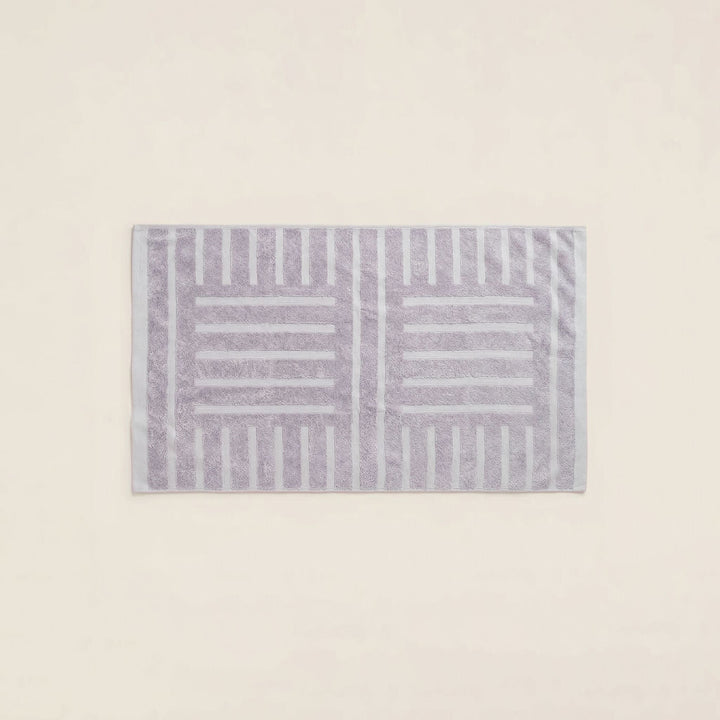 Rectangular striped cotton towel in lilac and light gray, neatly folded