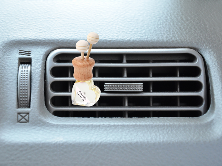 Car vent diffuser with wooden holder and glass bottle clipped to car air vent