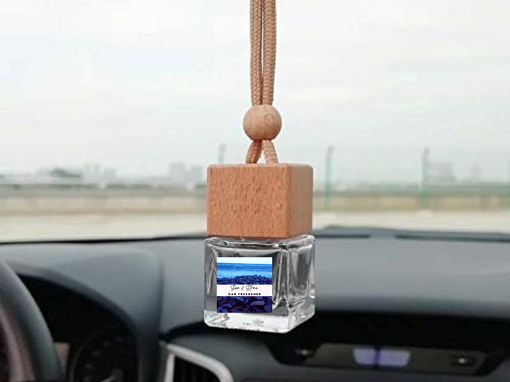 Hanging car freshener on dashboard with square clear glass bottle and rope hanger.