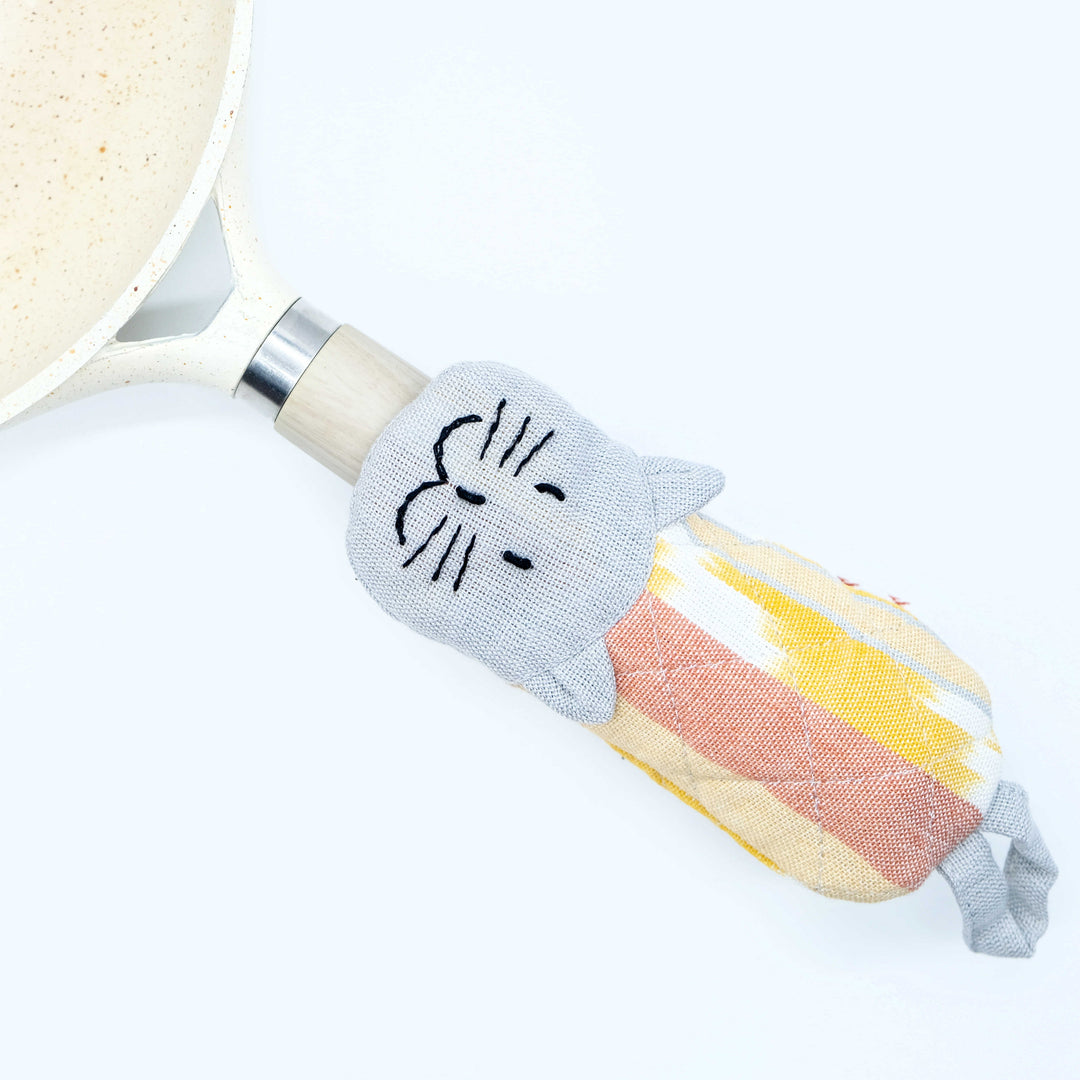 Cat skillet handle holder, light gray striped sleeve with red-yellow striped cat body.