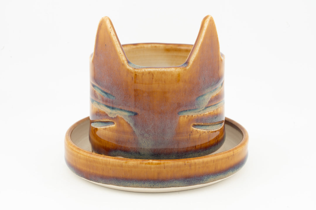 Orange-brown cat-shaped planter with circular saucer, glossy glazed finish