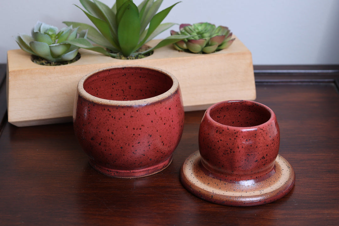 Ceramic butter dish set with two red speckled cups on tan bases, round plates