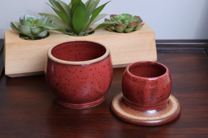 Ceramic butter dish set with two red speckled cups on tan bases, round plates