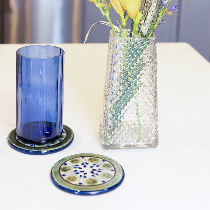 Round ceramic coaster with blue-and-green floral pattern and olive rim.