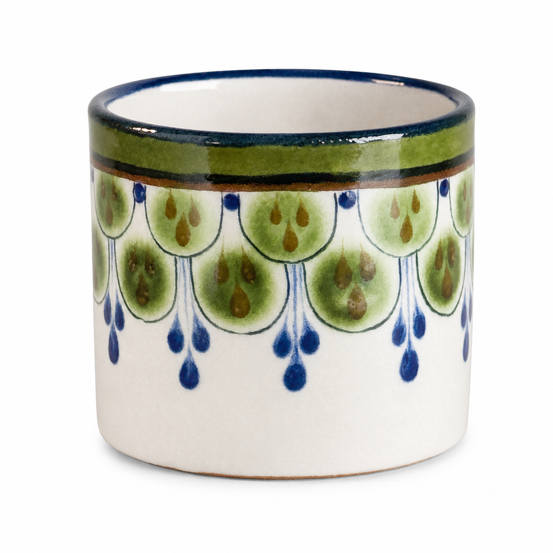 Stoneware cup close-up with green-and-blue raindrop pattern and glossy blue rim.