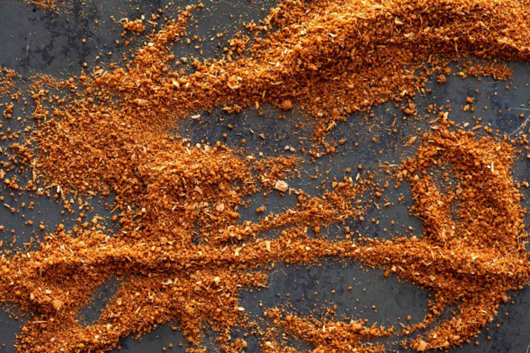 Ground red spice powder sprinkled in a heart-like pattern on dark surface