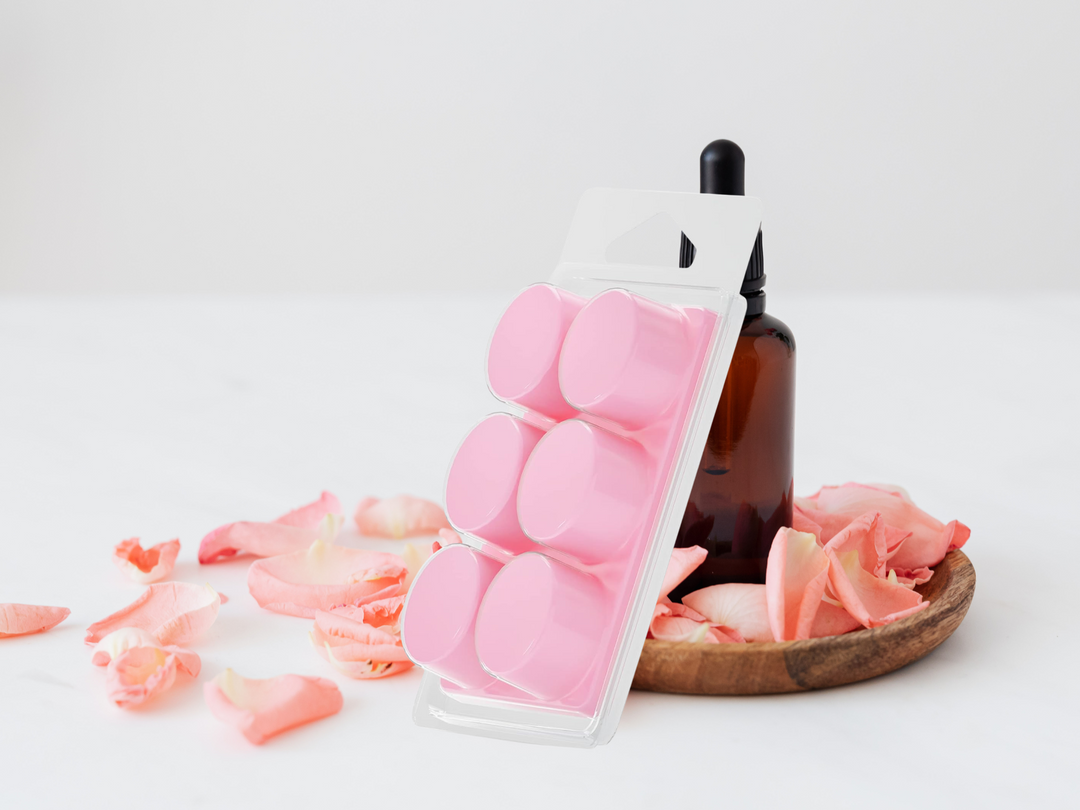 Clamshell wax melts with pink round wax discs in a clear tray beside petals