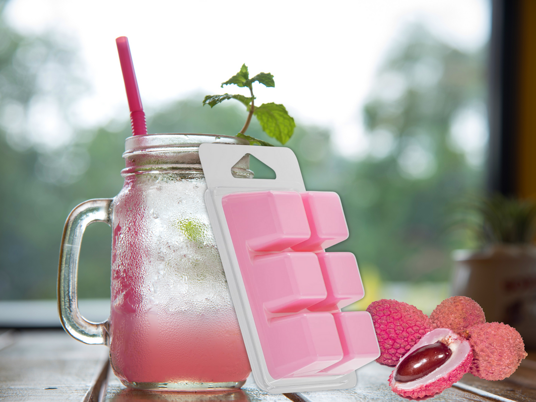Pink wax melt clamshell with cube melts beside a glass mug and strawberry decor