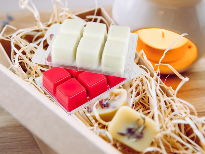 Cream and red wax melt cubes in clamshells with straw and small lit candle