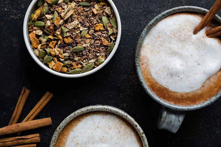 Chai tea in a ceramic mug with loose tea leaves in a white bowl