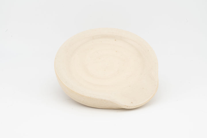 Cream ceramic spoon rest with smooth round surface and shallow rim