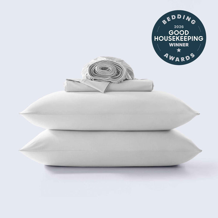 White cooling sheet set with matching pillowcases, neatly folded and rolled