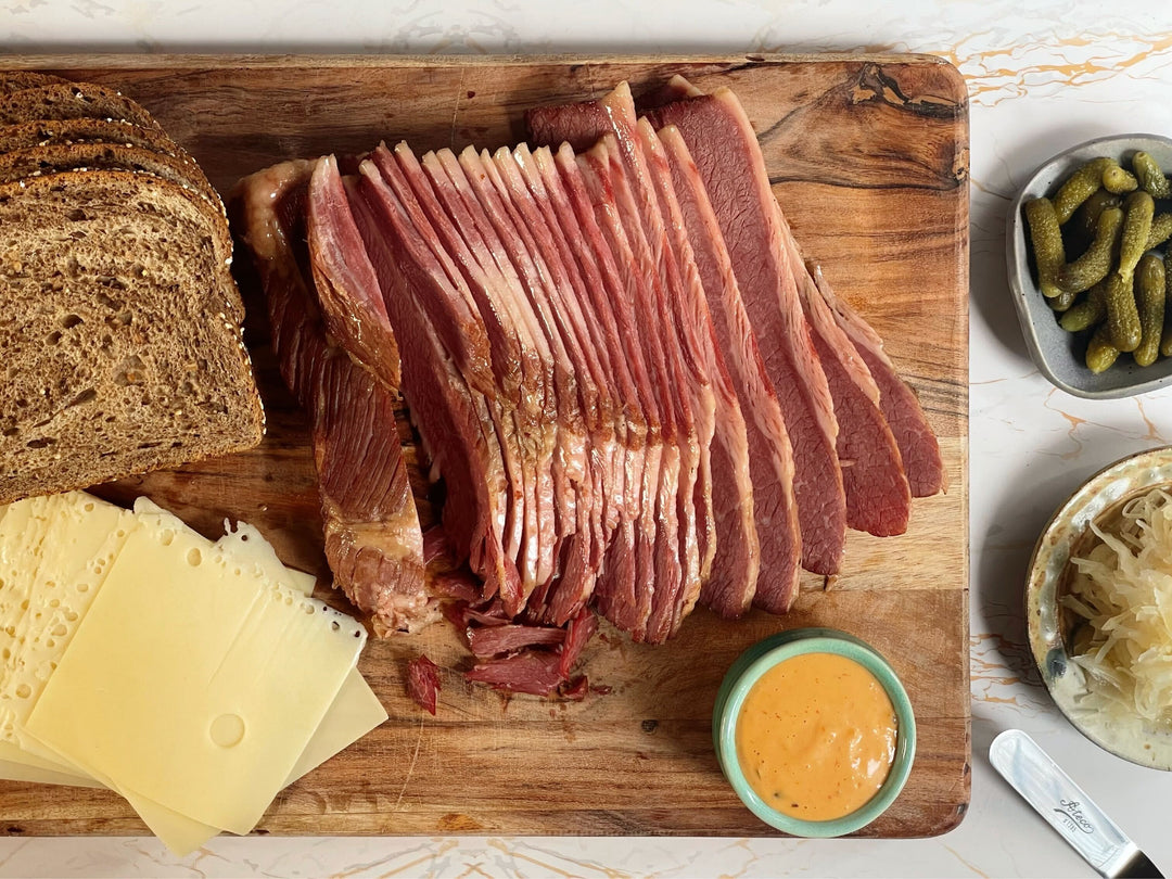 Corned beef cure kit, sliced cured brisket on wooden board with cheese and mustard
