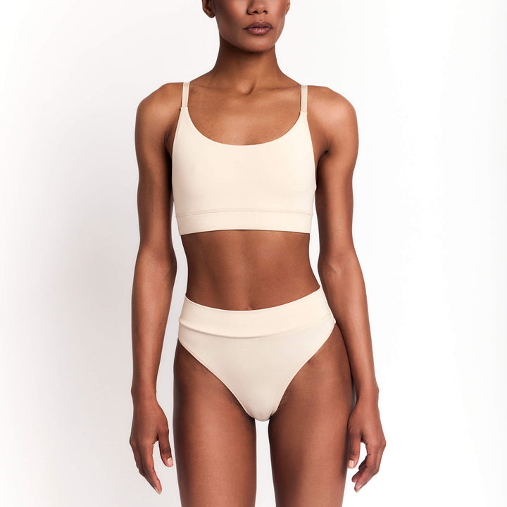 Cheeky tanga briefs in nude/latte, low-rise with smooth fabric and minimal coverage.