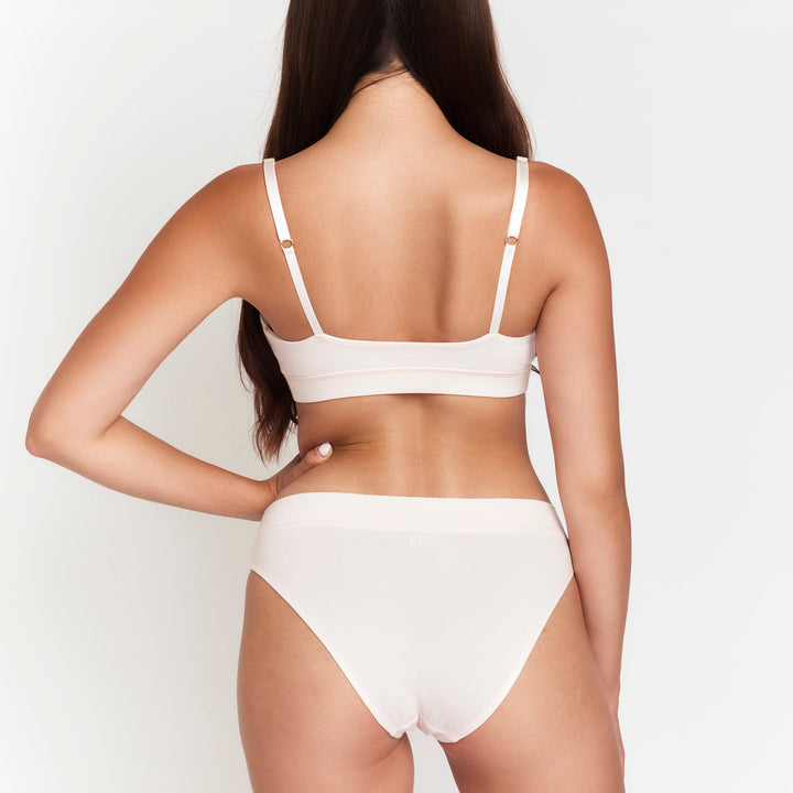 Cheeky tanga briefs in light cream, low-rise with minimal back coverage.
