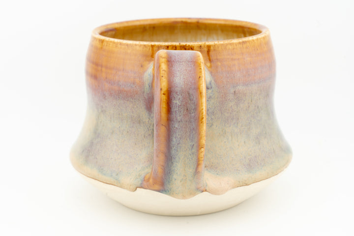 Wide ceramic mug showing front center seam and amber-to-cream glaze with blue tint