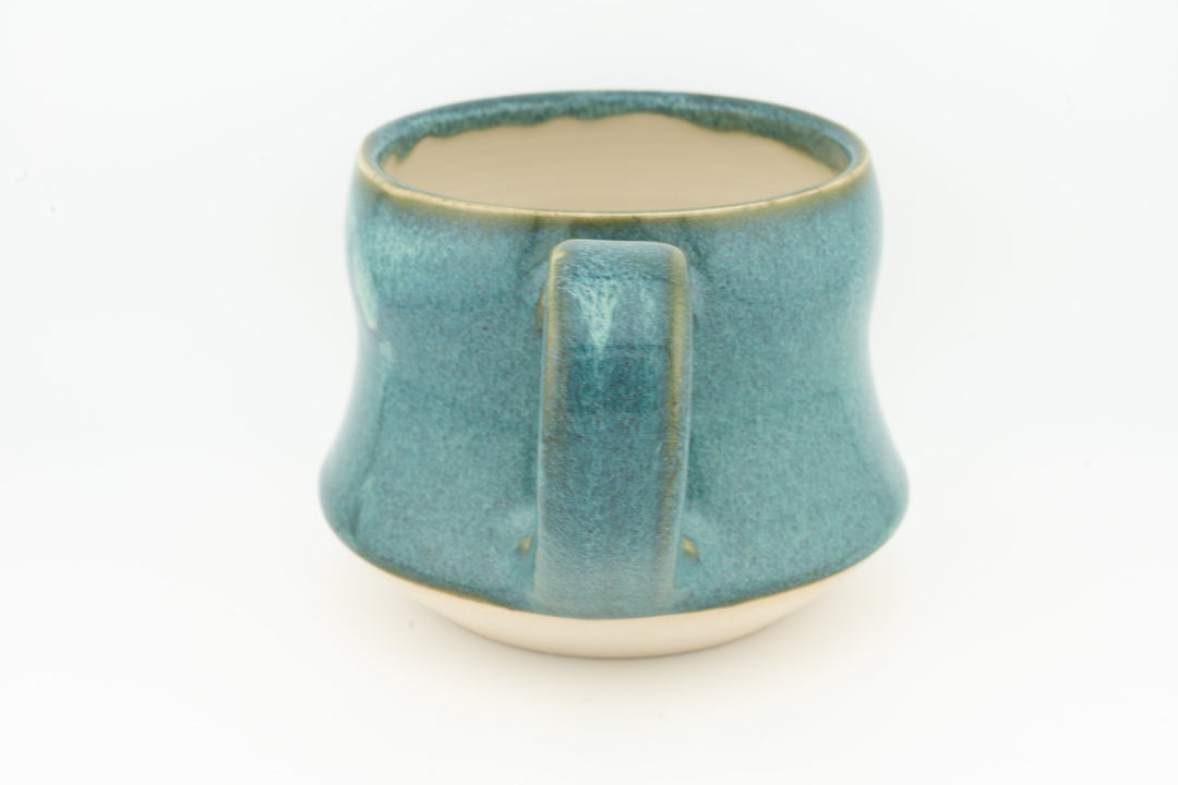 Turquoise ceramic mug with wide handle, smooth glaze and pale drips on front